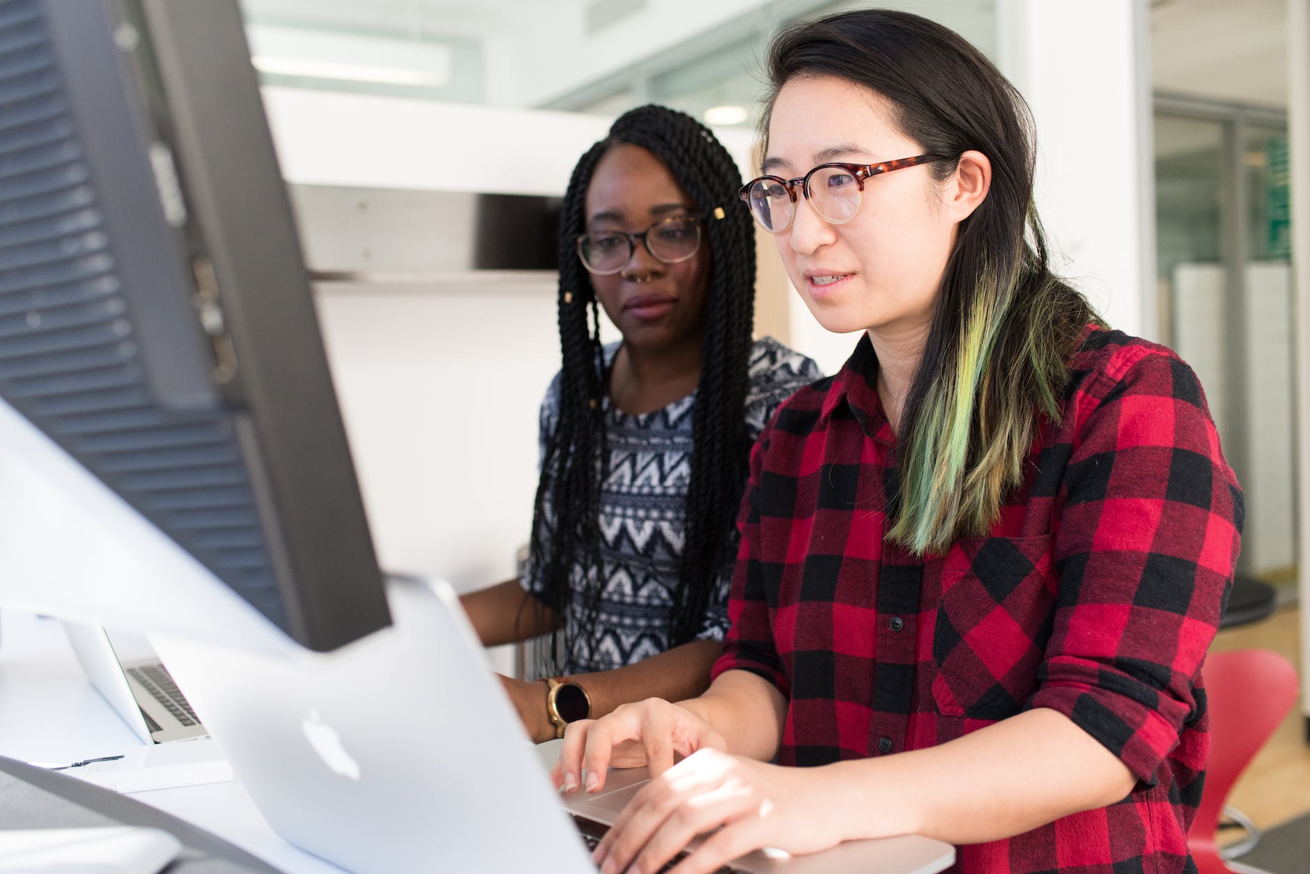 woman wearing red and black checkered blouse using macbook